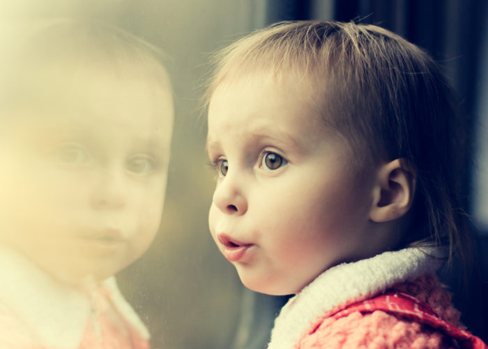 A boy rides on a train and looking out the window.